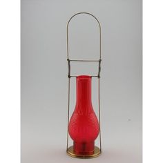 a red vase sitting on top of a metal stand with a wire around it's base