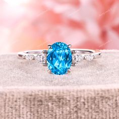 a ring with a blue stone surrounded by three white diamonds on top of a piece of cloth