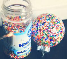 a jar filled with sprinkles next to a plastic ball on a table