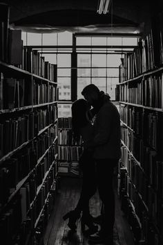 two people are kissing in the middle of a library