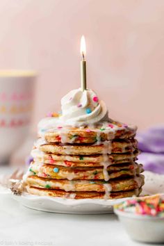 a stack of pancakes with white frosting and sprinkles on a plate