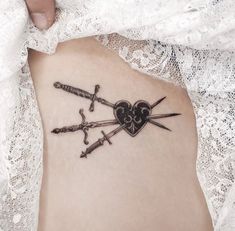 a woman's stomach with two crossed swords and a heart tattoo