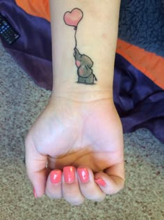 a small elephant with a heart shaped balloon tattoo on the wrist is shown in this image