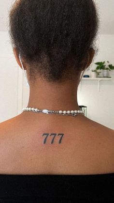 the back of a woman's neck has a tattoo on it that reads 777