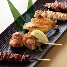 several skewered meats and vegetables on a black plate