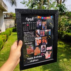 a person holding up a black frame with photos on it in front of a house