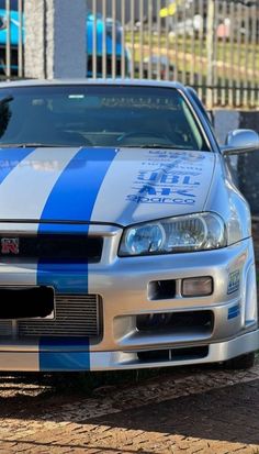 a blue and white striped car parked in front of a building with a black cat sitting on the hood