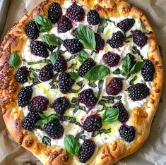 a pizza with blackberries and spinach on it