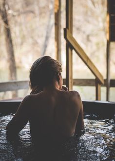 a person sitting in a hot tub with trees in the background