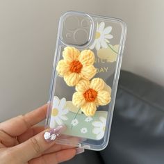 a person holding up a phone case with crochet flowers on the front and sides