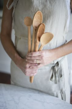 a woman holding wooden spoons in her hands