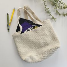 a tote bag sitting on top of a table next to a pencil