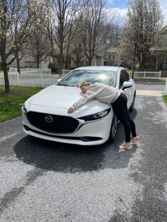 a woman leaning on the hood of a white car