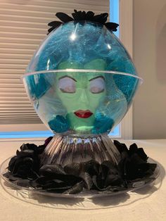 there is a glass ball with a face on it and black flowers in the bottom