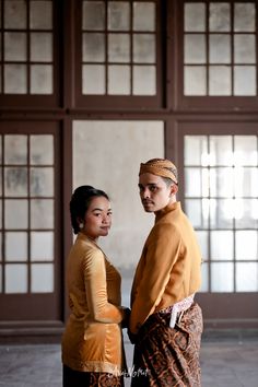 two people standing next to each other in front of windows