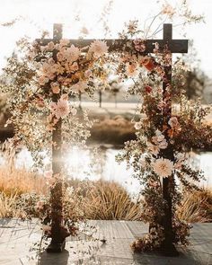 an outdoor wedding ceremony with flowers and greenery on the altar, surrounded by water