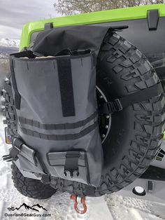 the back end of a green jeep with its cargo bag on it's tire