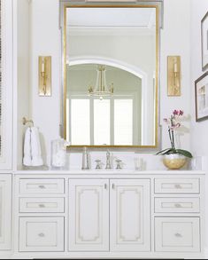 a bathroom with white cabinets and gold accents