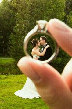 a bride and groom holding their wedding ring in front of the photographer's face