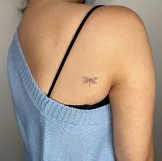 a woman with a small dragonfly tattoo on her upper back shoulder and arm,