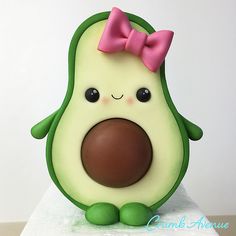 an avocado with a pink bow on it's head sitting on a white surface