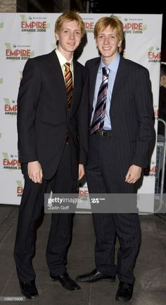 two men in suits standing next to each other on the red carpet at an event