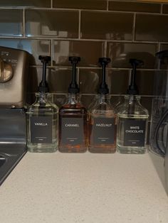 three bottles of hand soap sitting on top of a counter next to a toaster