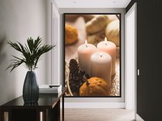 three lit candles sitting on top of a table next to a vase filled with pine cones