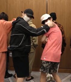 two men are hugging each other in front of a group of people wearing face masks