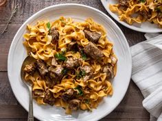 two white plates filled with pasta and meat