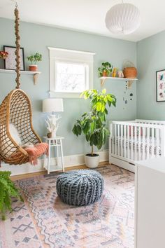 a baby's room with a hammock chair, rug and potted plants