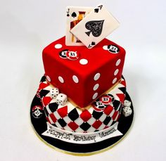 a three tiered cake with dice and playing cards on the top, sitting on a plate