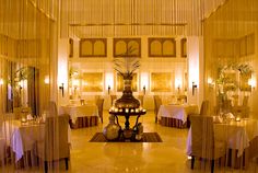 a fancy dining room with white tablecloths and tall vase on the centerpiece