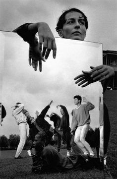 several people are standing in front of a mirror with their hands on the reflection, and one person is reaching for something