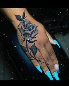 a woman's hand with blue nails and a rose tattoo on it