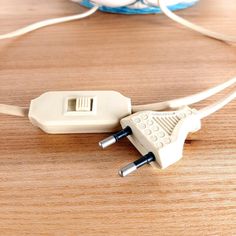 an electronic device plugged into a charger on a wooden table with wires attached to it