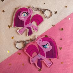 two pink pony keychains sitting next to each other on top of a table