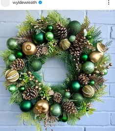 a wreath with green and gold ornaments hanging from it's side on a brick wall