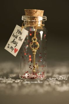 a bottle with a key inside and a tag attached to the top that says you hold the key to my heart