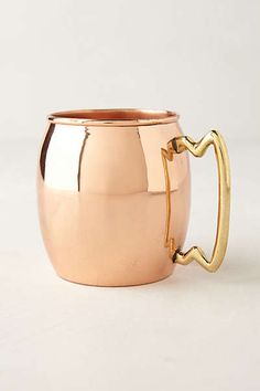 a shiny metal cup with a handle on a white surface, ready to be used as a garnish