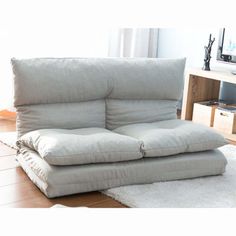 a white couch sitting on top of a rug in a living room next to a window