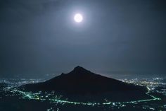 the moon is shining over a city at night