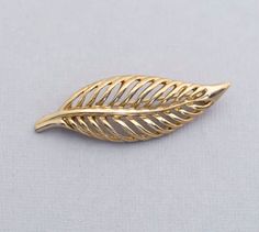 A gold tone brooch that resembles a leaf. Store Notes - This is the exact item you'll receive!  - USPS first class within 1 business day of purchase.  - Items are packaged in a jewelry box unless they are too big.  - Open to best offer - If you have any questions please ask! Thanks Tags Vintage Fierce Leaf Gold Tone Brooch, Art Nouveau Stylish Brooch, Intricate Elven Leaves Brooch Gold Leaf Brooch For Gift, Art Nouveau Yellow Gold Brooch Jewelry, Bamboo Jewelry, Art Nouveau Filigree Brooch For Collectors, Luxury Yellow Gold Art Nouveau Brooch, Gold Enamel Art Nouveau Brooches, Luxury Gold Art Nouveau Brooches, Brooch Art, Faux Bamboo