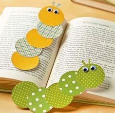 an open book sitting on top of a table next to a paper caterpillar