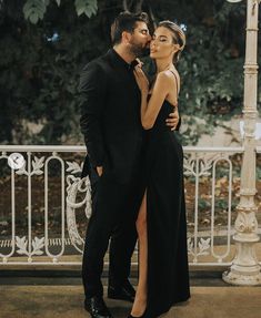 a man and woman standing next to each other in front of a street light with their arms around each other