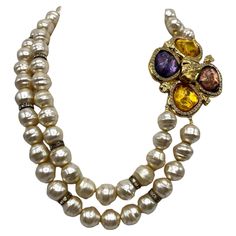 This vintage 1980s Robert Goosens for Yves Saint Laurent pearl necklace is a stunning piece of jewelry. The two strand design adds dimension and elegance to the piece, while the poured resin flower clasp is a statement feature. The large flower clasp, measuring 3 inches, is adorned with clear gold, purple, and plum poured resin stones, adding a pop of color and sparkle. The faux Baroque glass center pearls, each measuring 0.5 inches in diameter, are accented with rhinestone rondelles, adding a touch of glamour to the necklace. The wearable length of the necklace is 21 inches, with the shortest strand measuring 17 inches and the longest strand measuring 21 inches. Overall, this necklace is a beautiful example of vintage Yves Saint Laurent jewelry and would make a striking addition to any co Smokey Topaz, Citrine Stone, Color Dorado, Multi Strand Necklace, Ethnic Jewelry, Topaz Gemstone, Glass Necklace, Diamond Art, Strand Necklace