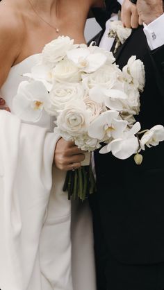 the bride and groom are posing together for a photo with white flowers in their bouquet