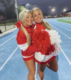 two cheerleaders hugging each other on a track