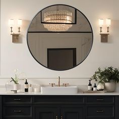 a bathroom vanity with a round mirror above it and lights on the wall behind it