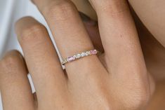 a woman's hand with a pink and white diamond ring on her left hand